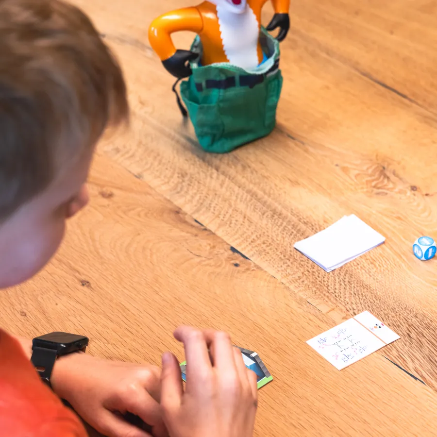 Kind oefent met leerkaarten en spelmateriaal aan de praktijktafel