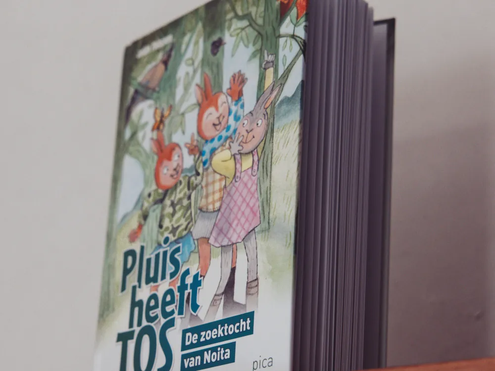 Het boek 'Pluis heeft TOS' op de boekenplank in de praktijk