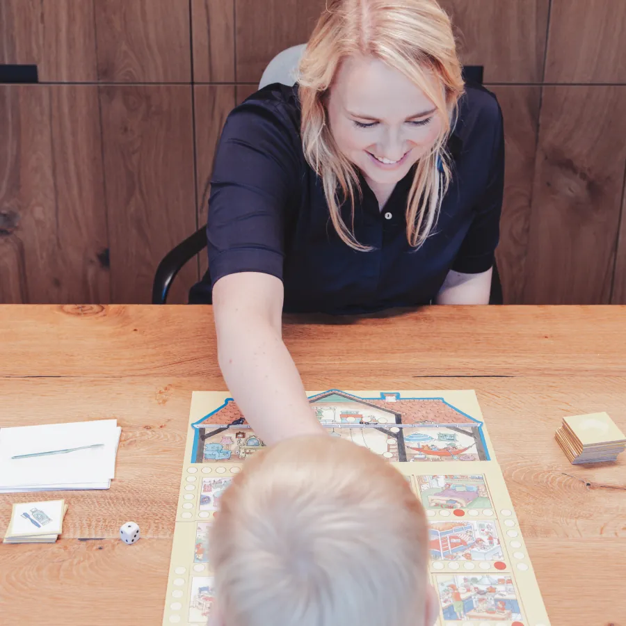 Logopediste speelt een taalspel met een kind aan de praktijktafel