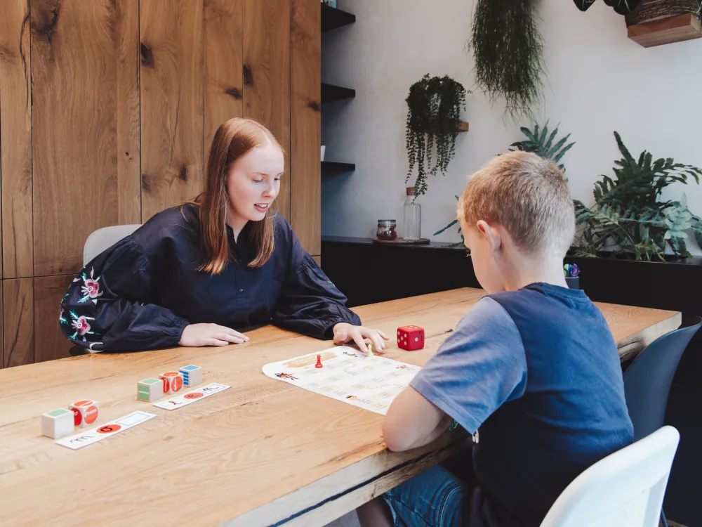 Franne speelt een bordspel met een jongen aan de praktijktafel
